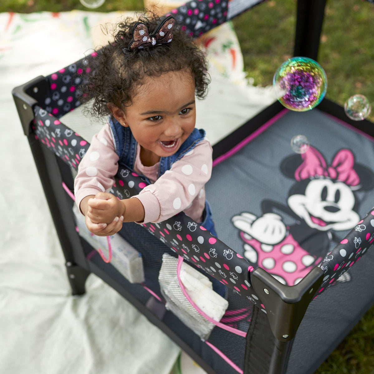 Disney Baby 3D Ultra Play Yard with Bassinet, Toy Bar & Carry Bag – Modern Minnie – Portable Infant Playpen & Travel Crib